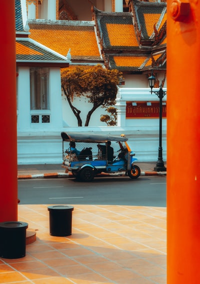 白天停在白楼旁的红黑两色汽车人力车